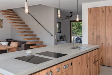 Küchendesign von VOIT aus rustikaler Eiche und Beton, im Hintergrund geschlossene Küchenschränke aus Eiche